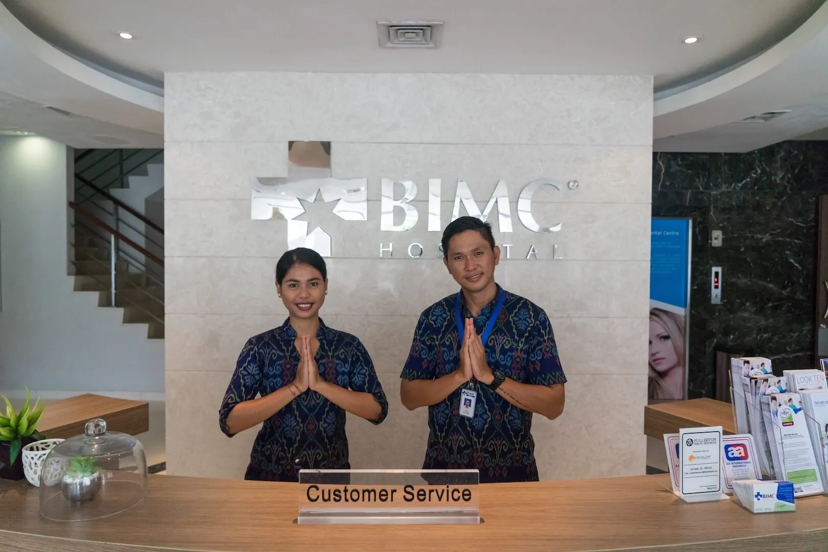 Two staff at the reception counter of BIMC CosMedic Bali, a plastic surgery clinic in Bali